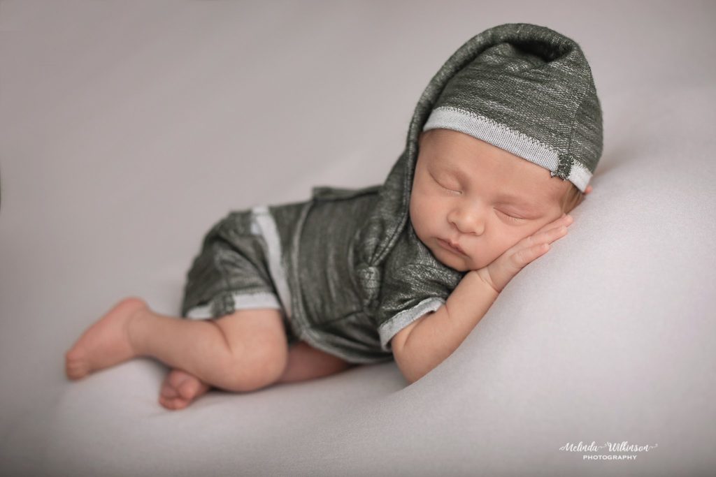Newborn boy in green outfit with sleepy hat