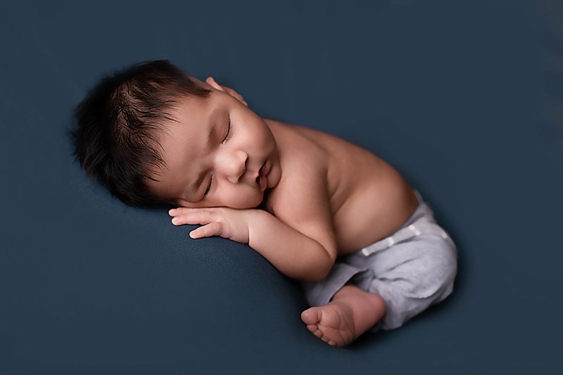 Newborn boy sleeping on blue