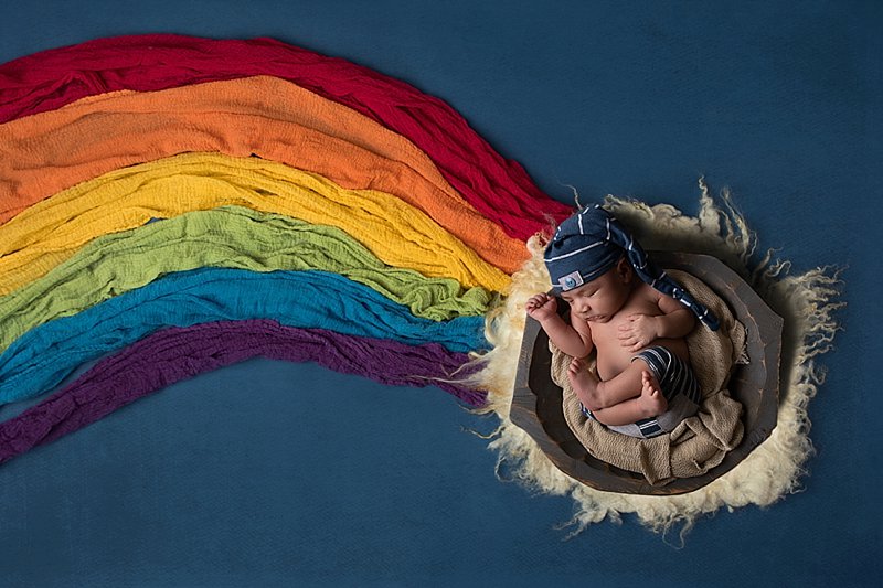 Newborn baby in a bow with a rainbow