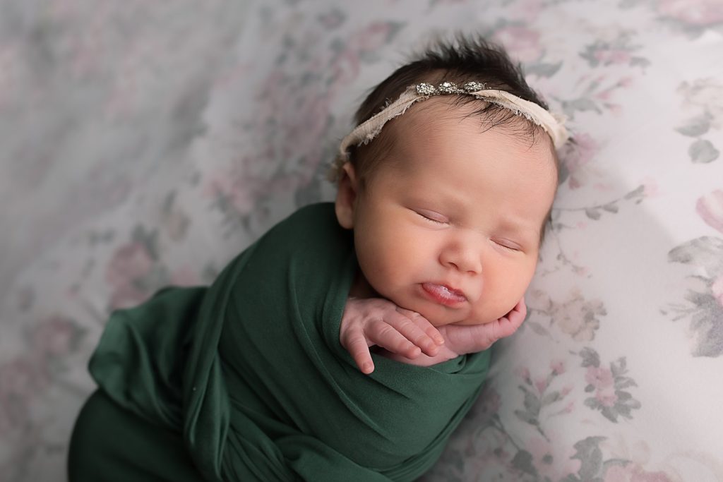 Newborn girl in green wrap with floral