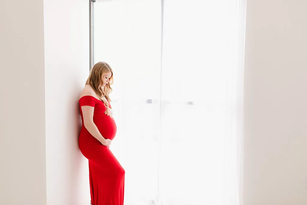 Pregnant woman in a red gown holding her stomach