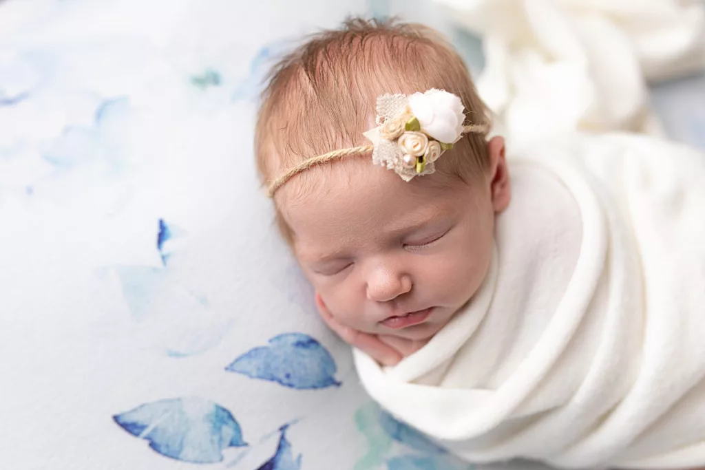 newborn girl with headband on but floral backdrop