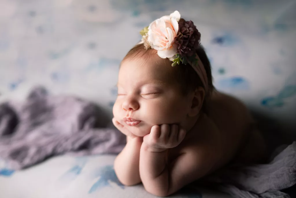 Newborn baby girl on a floral backdrop with a large flower headband