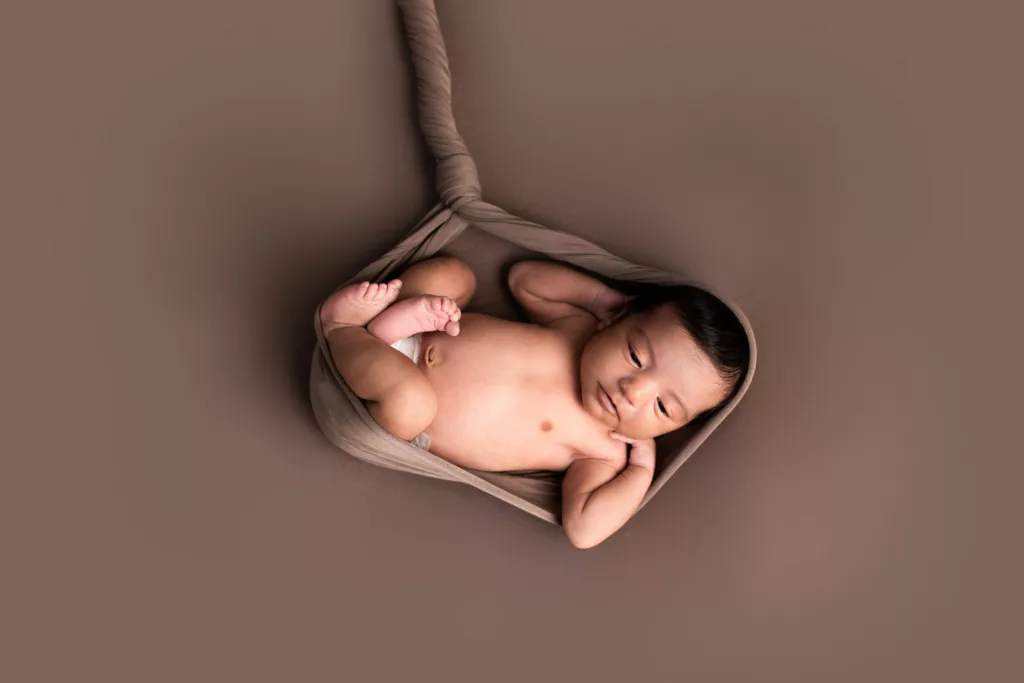 Newborn girl with a brown wrap and backdrop